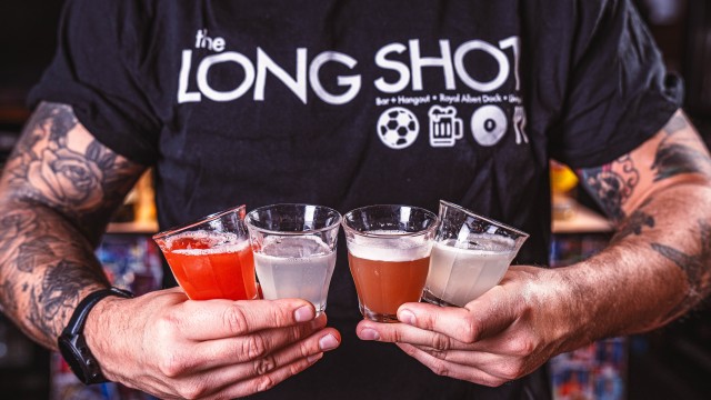 Man holding shots in sports bar